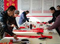 志愿者走进乡村送福，写春联拍全家福