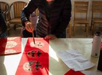 志愿者走进乡村送福，写春联拍全家福