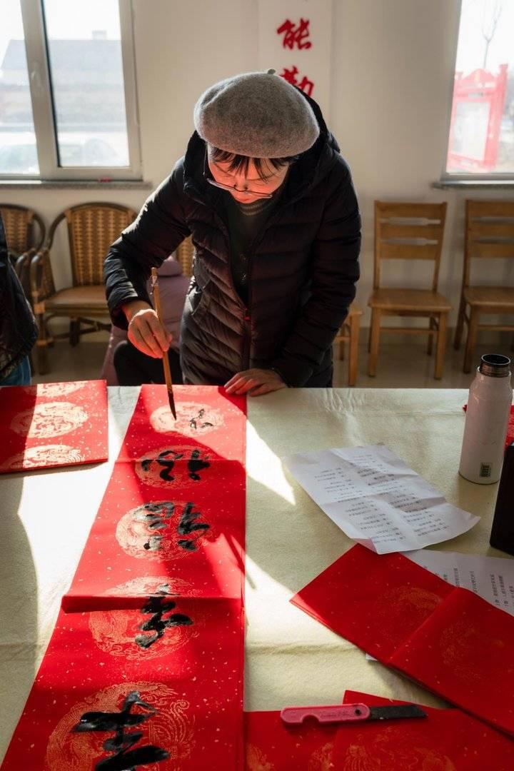 志愿者走进乡村送福，写春联拍全家福