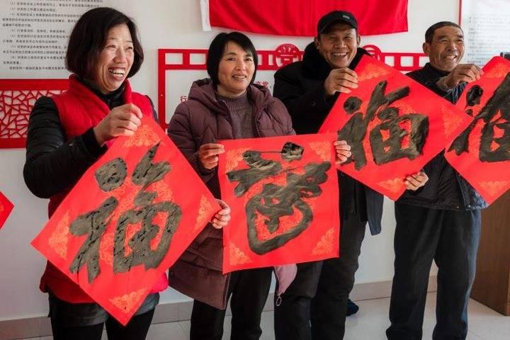 志愿者走进乡村送福，写春联拍全家福