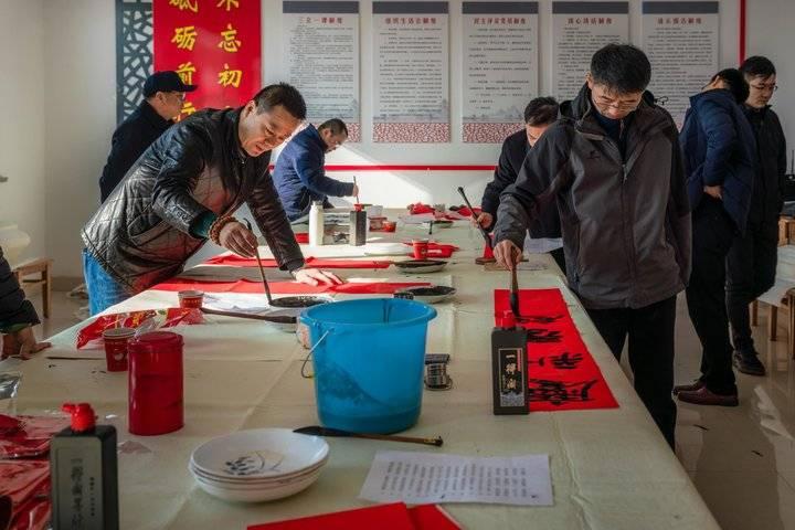 志愿者走进乡村送福，写春联拍全家福